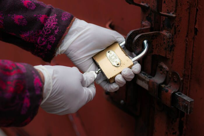 Person With Gloves Opening Lock Using A Key 