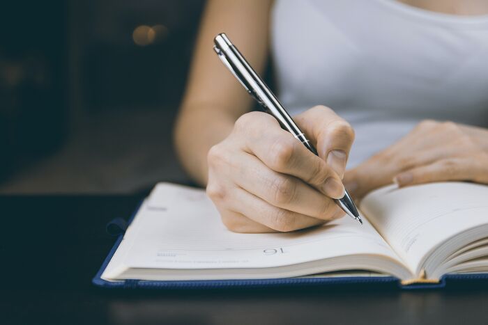 Woman Writing In To Notepad 