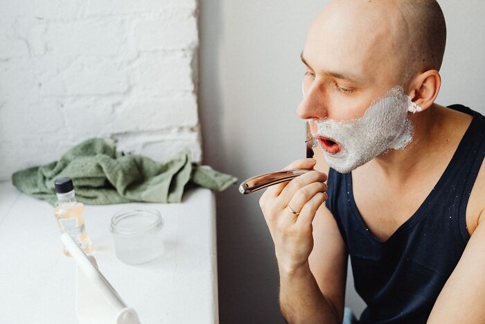 Man Shaving His Beard In Front Of The Mirror 