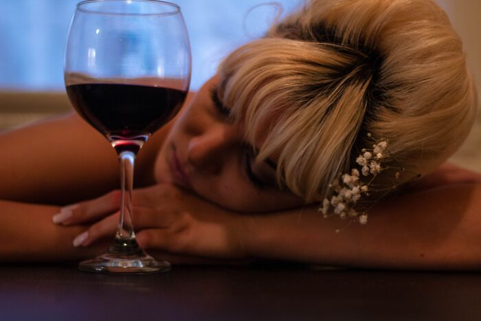 Woman Sleeping On The Table Besides A Wine Glass 