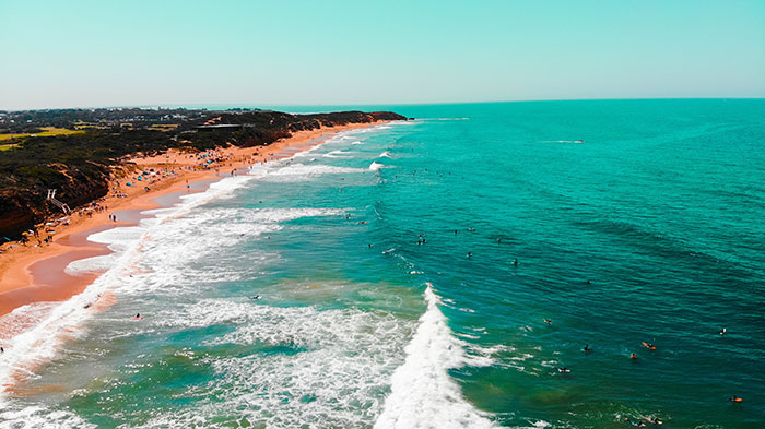 A view of a beach with people swimming in the water