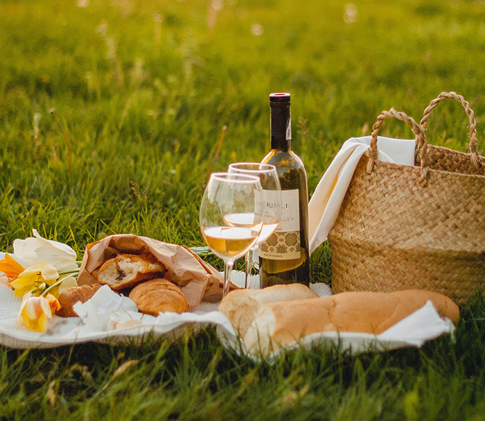 Picture of picnic outside with glass of wine, flowers and bread