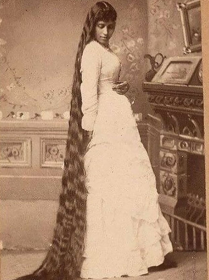 Una dama victoriana con un cabello muy largo en una foto de moda, alrededor de la década de 1890