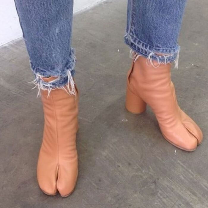 Weird shoes with split-toe design in tan leather, paired with frayed jeans.