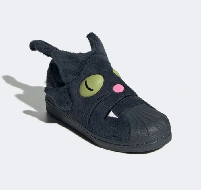 Weird shoes featuring a furry black cat design with green eyes and pink nose.