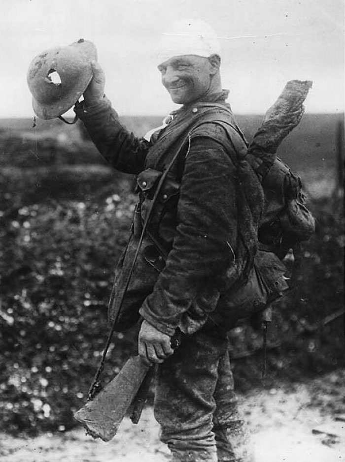 Un afortunado soldado británico sonríe mientras muestra su casco dañado, 1917