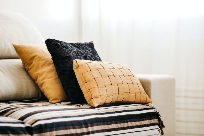 Home organization idea with decorative pillows on a patterned couch, featuring woven and textured designs for stylish living room decor.