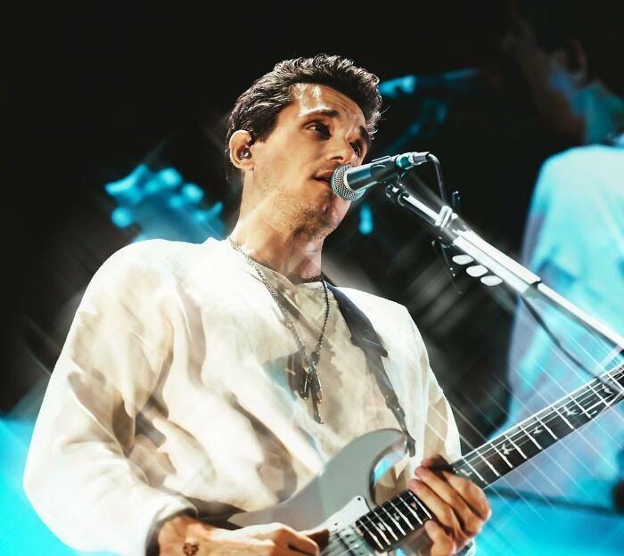 John Mayer singing and playing guitar on stage, representing celebrities who never married yet still found love.