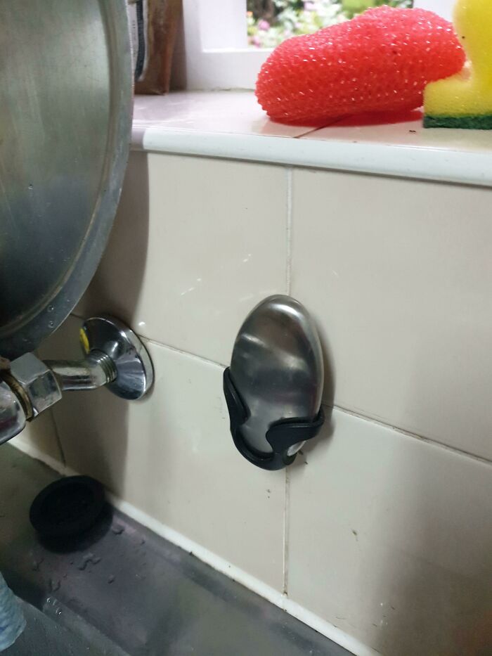 ¿Qué es esa cosa metálica ovalada en un soporte de plástico que está en la pared de la cocina, junto al fregadero?
