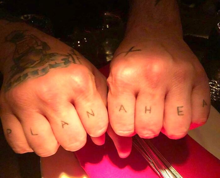 Two hands with knuckle tattoos reading "PLAN AHEA," a funny tattoo fail.