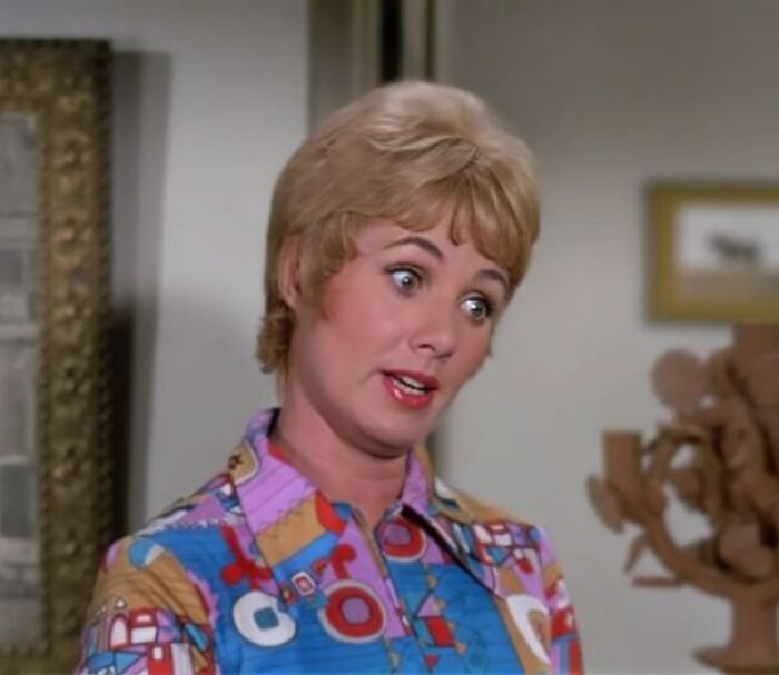 Shirley Partridge in the colorful geometric shirt is talking with her eyes wide open