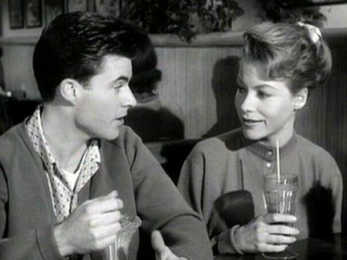 Harriet Nelson sitting with a man and drinking a cocktail