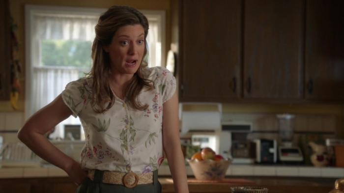 Mary Cooper in a white floral blouse is talking in the kitchen