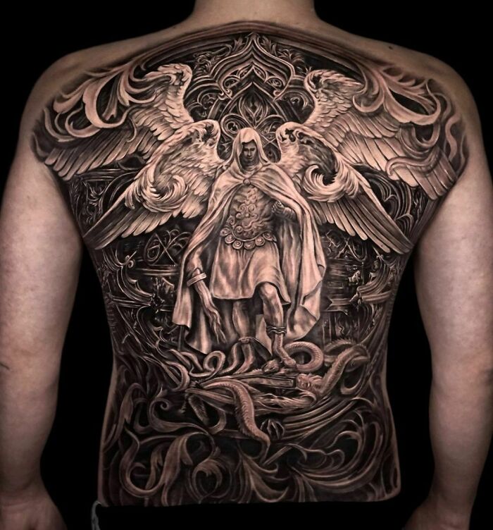 Super realistic tattoo of an angel with wings covering a person's back, displaying intricate details and shading.