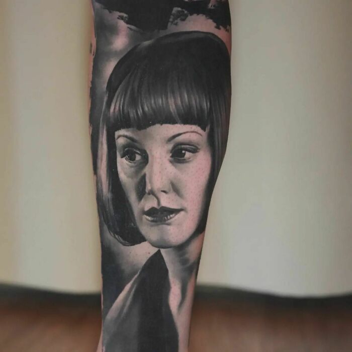 Super realistic tattoo depicting a woman's face in black and gray tones on the forearm.