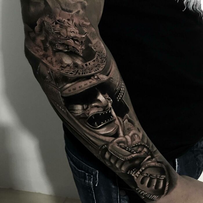 Realistic tattoo of a fierce samurai and dragon design on a man's arm, showcasing intricate detailing.