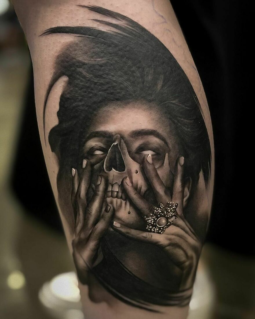 Dark woman face with skull mask tattoo, showing realistic detailing.