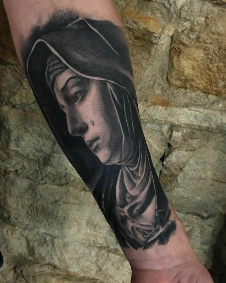 Realistic tattoo of Crying Virgin Mary on arm, showcasing exquisite detailing and lifelike features.