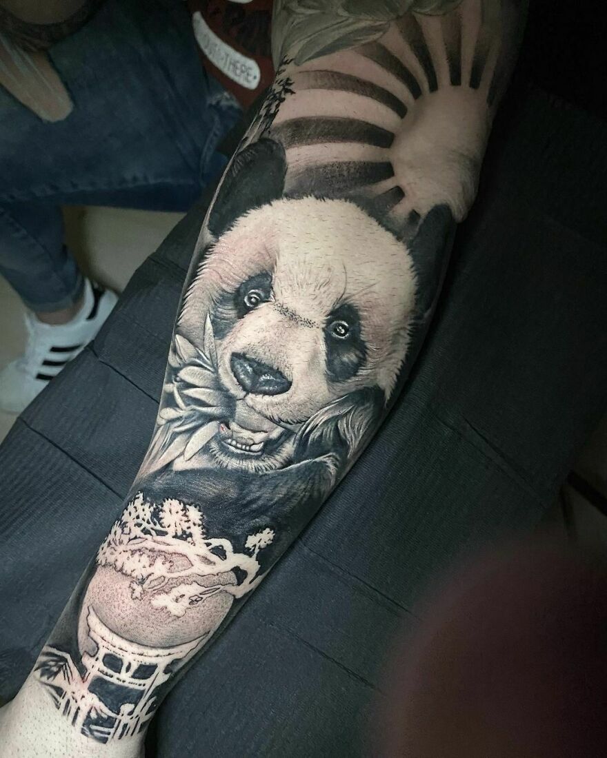 Panda eating bamboo and sun above its head tattoo on arm