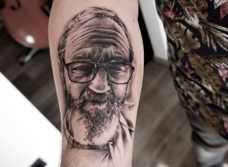 A super realistic tattoo of an older man with glasses, intricately detailed on a person's arm.