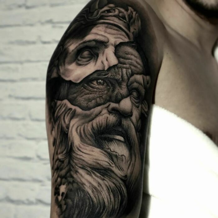 Realistic tattoo of an elderly man's face, intricately detailed on an upper arm.