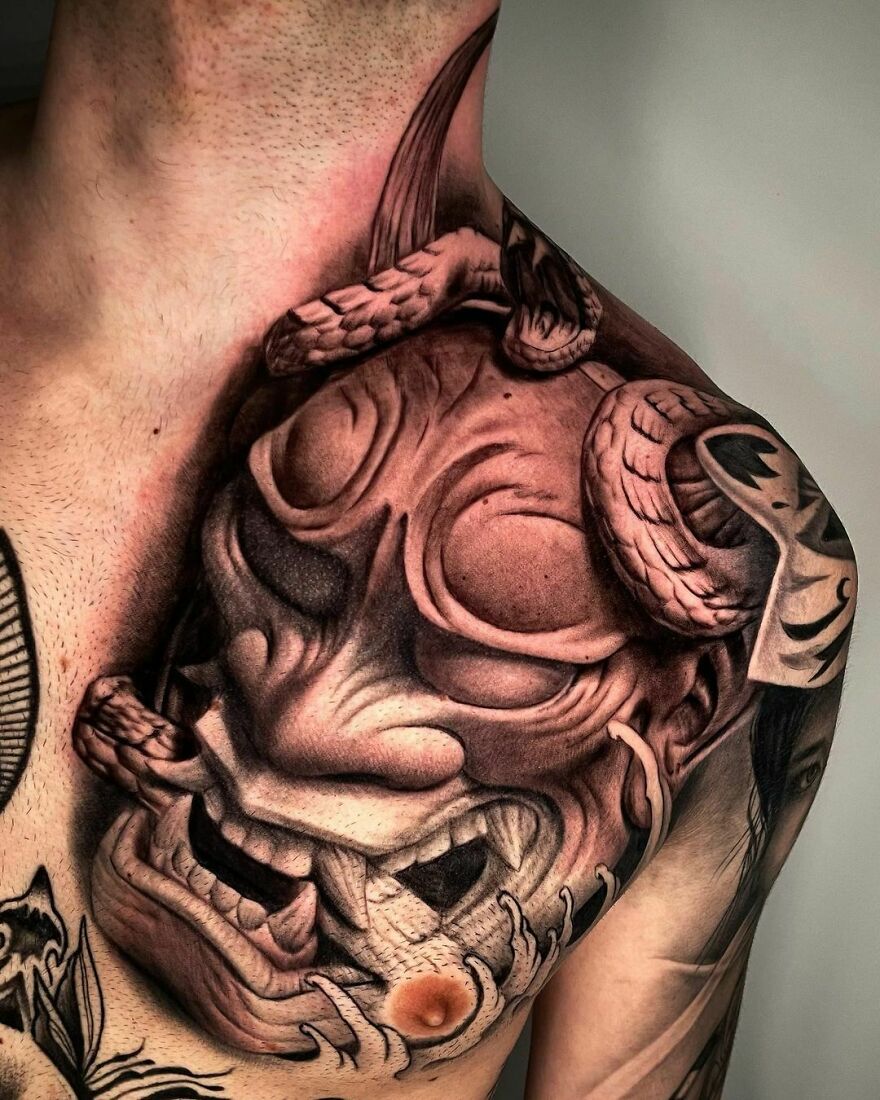 Japanese themed mask tattoo on chest showcasing realistic detailing.