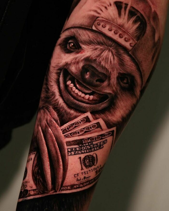 Realistic tattoo of a smiling sloth in a cap holding dollar bills, showcasing artistic detail and creativity.