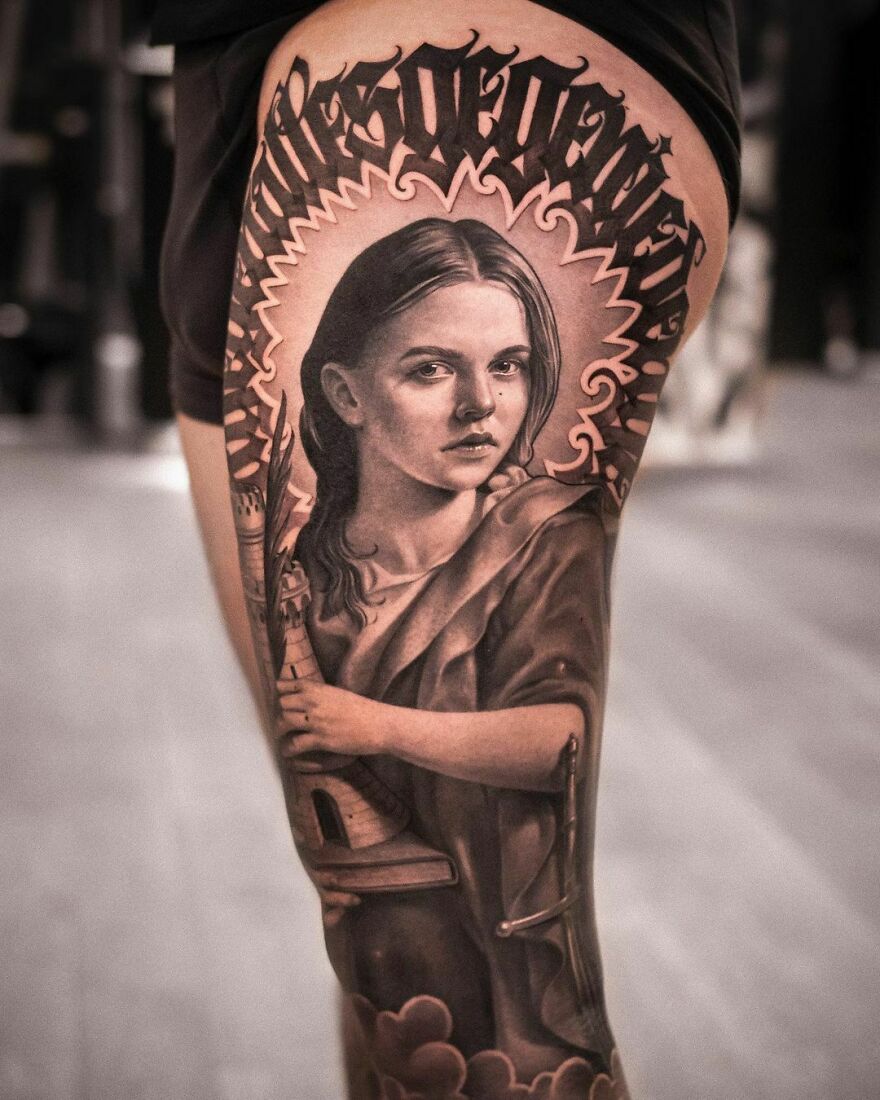 Realistic St. Barbara portrait tattoo on leg, featuring intricate detailing with graffiti art above.