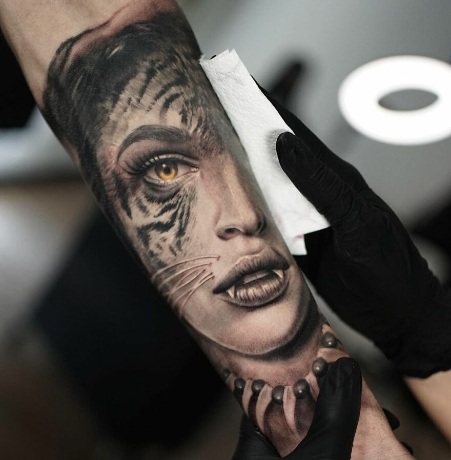 Realistic tattoo of woman's face merging with a tiger on arm, showcasing intricate detailing.