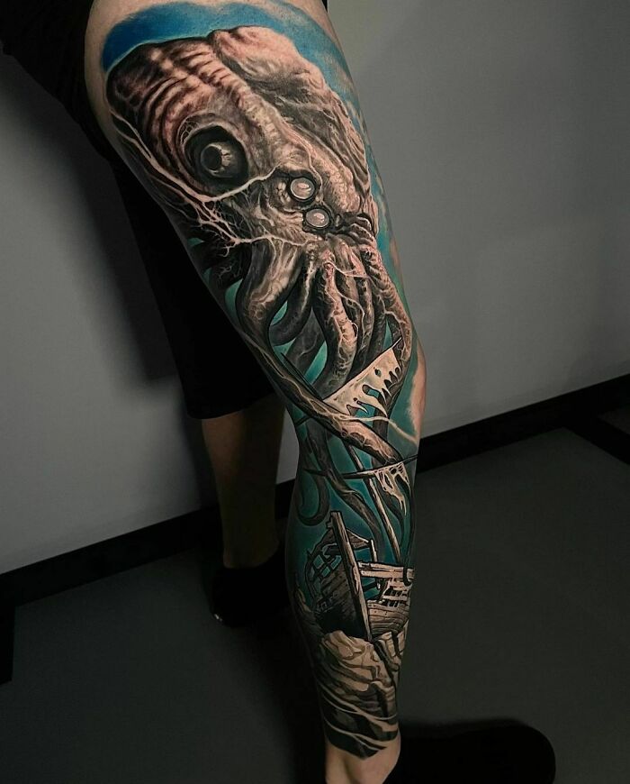 Realistic tattoo of a detailed squid covering a leg, featuring vivid colors and intricate shading.