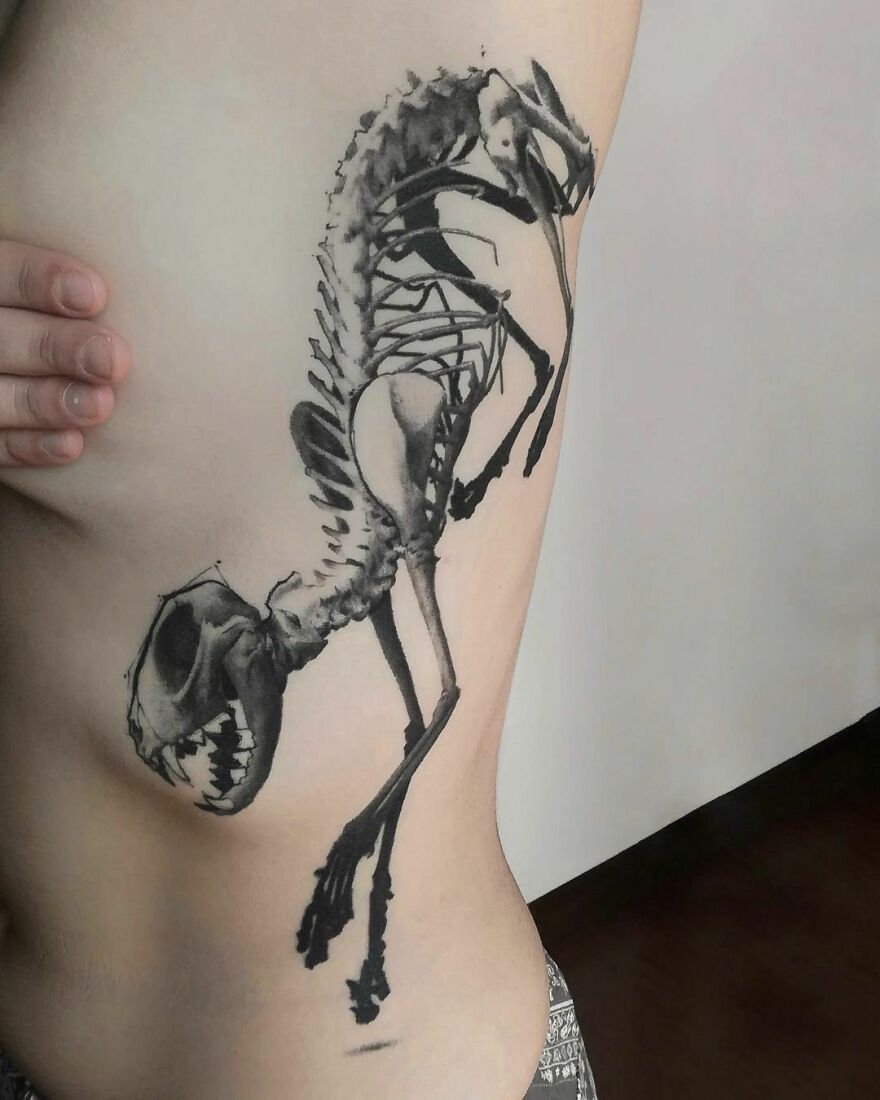 Super realistic cat skeleton tattoo showcasing intricate detailing on a person's side.
