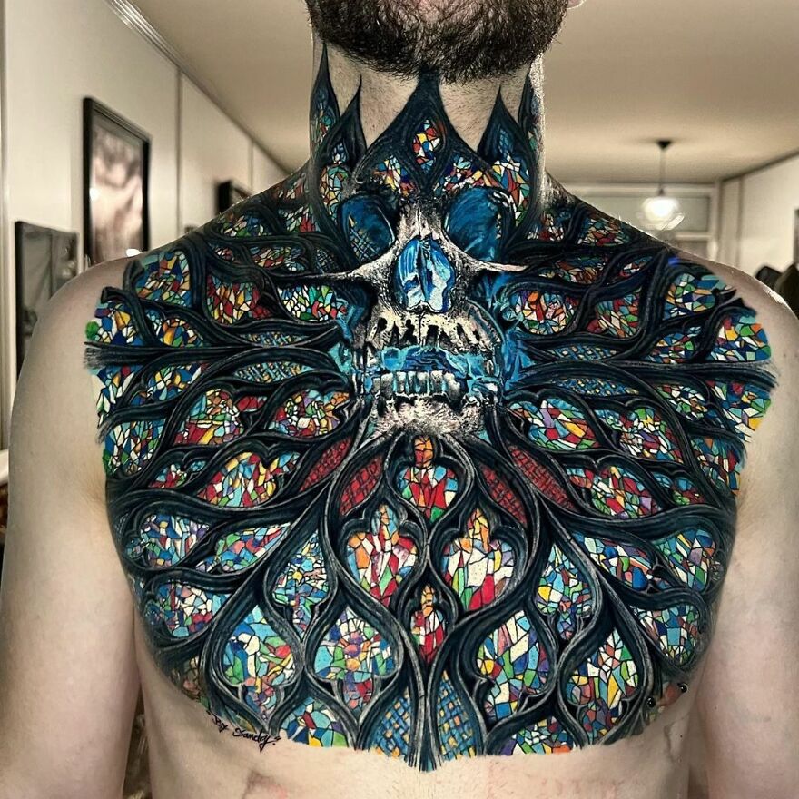 Super realistic tattoo of stained glass and skull design on a person's chest and neck, rich in color and detail.