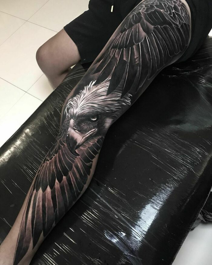 Realistic tattoo of an eagle covering a person's leg, showcasing intricate feathers and striking detail.