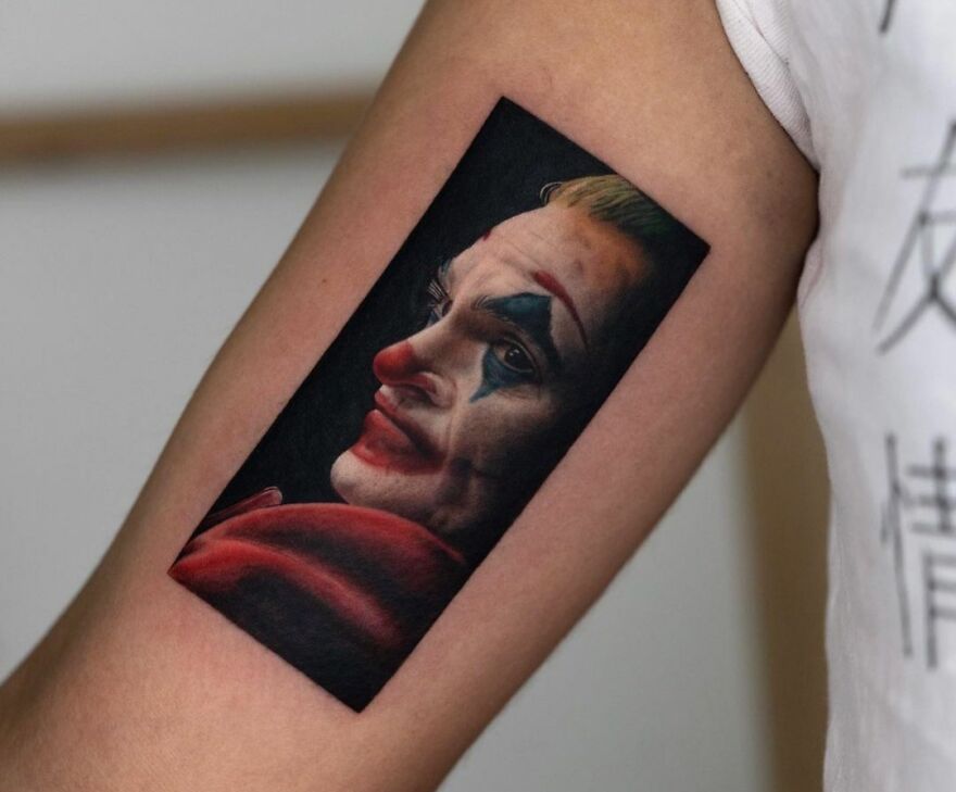 A super realistic tattoo of a clown face, showcasing amazing detail on a person's upper arm.