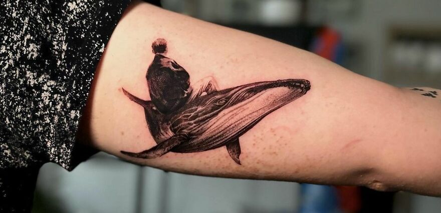 Human sitting on whale tattoo
