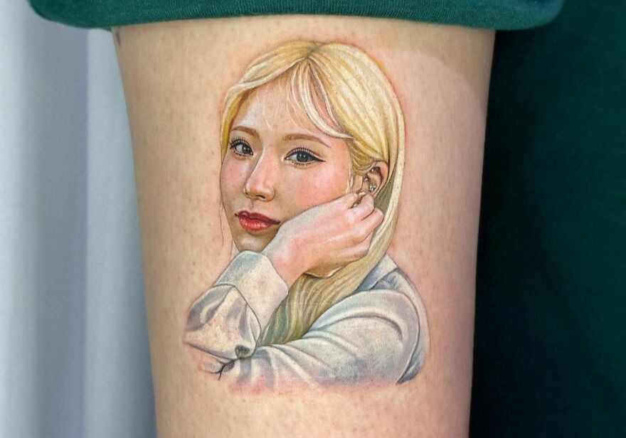 Realistic tattoo of a woman with blonde hair and a thoughtful expression on her face.