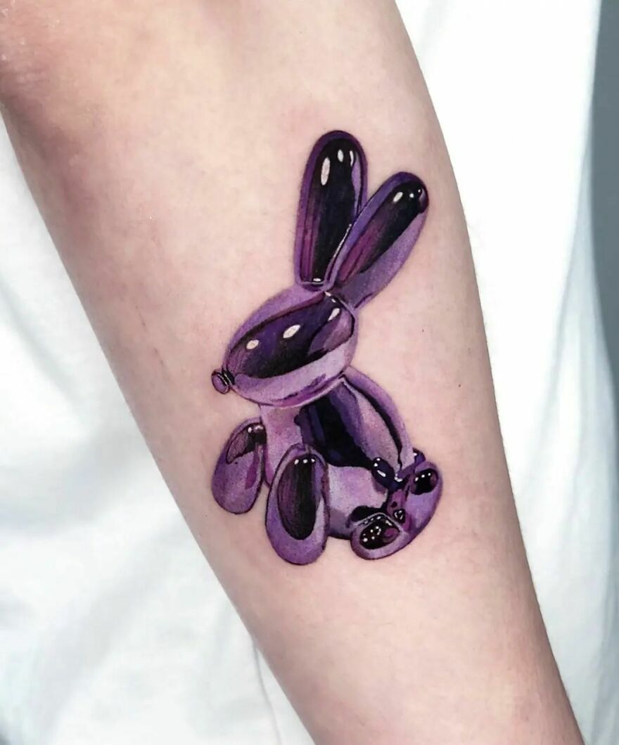 Purple rabbit balloon tattoo with super realistic detailing on forearm.