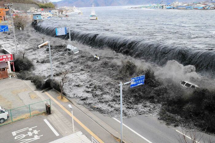 Aterrador tsunami con un muro de agua negra como el azabache desbordando el dique. Japón, marzo de 2011
