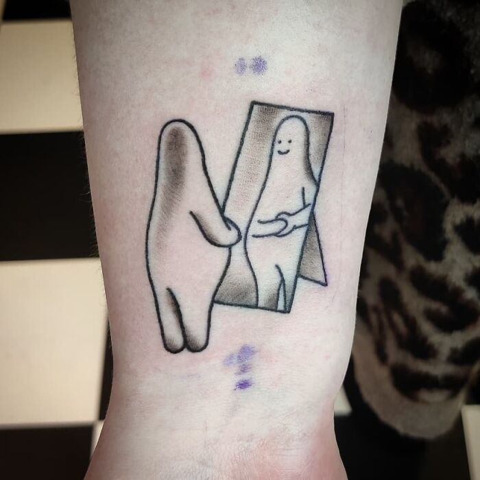 Self-love tattoo design of a figure embracing its reflection in the mirror on a person's arm.