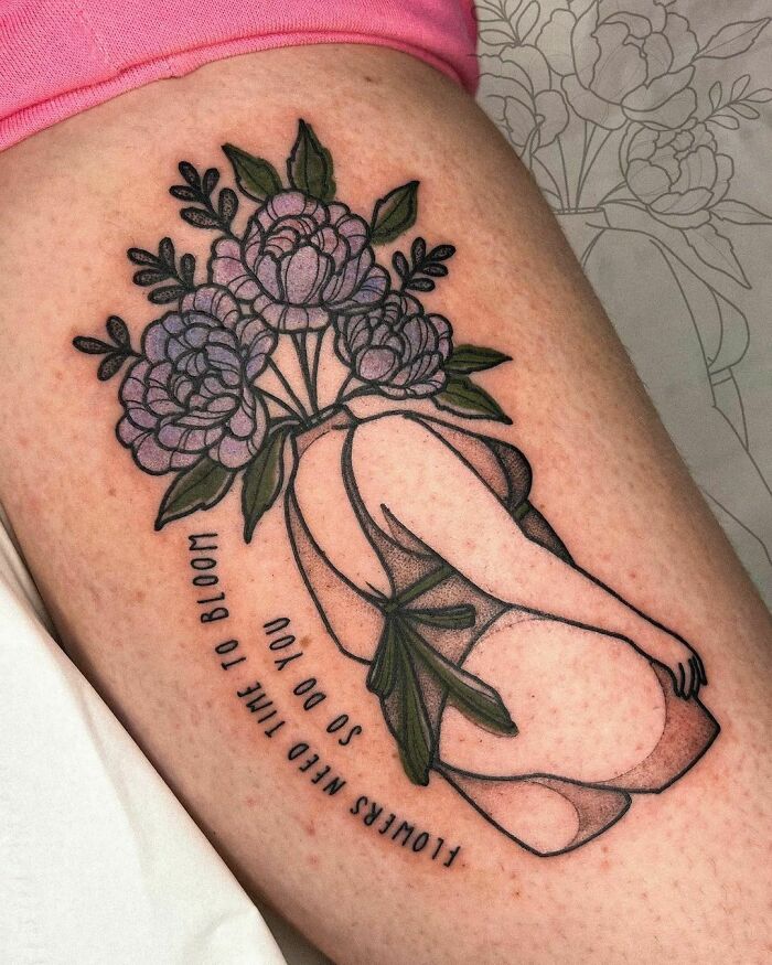 Self-love tattoo of a woman with floral head and inspirational text on the thigh.