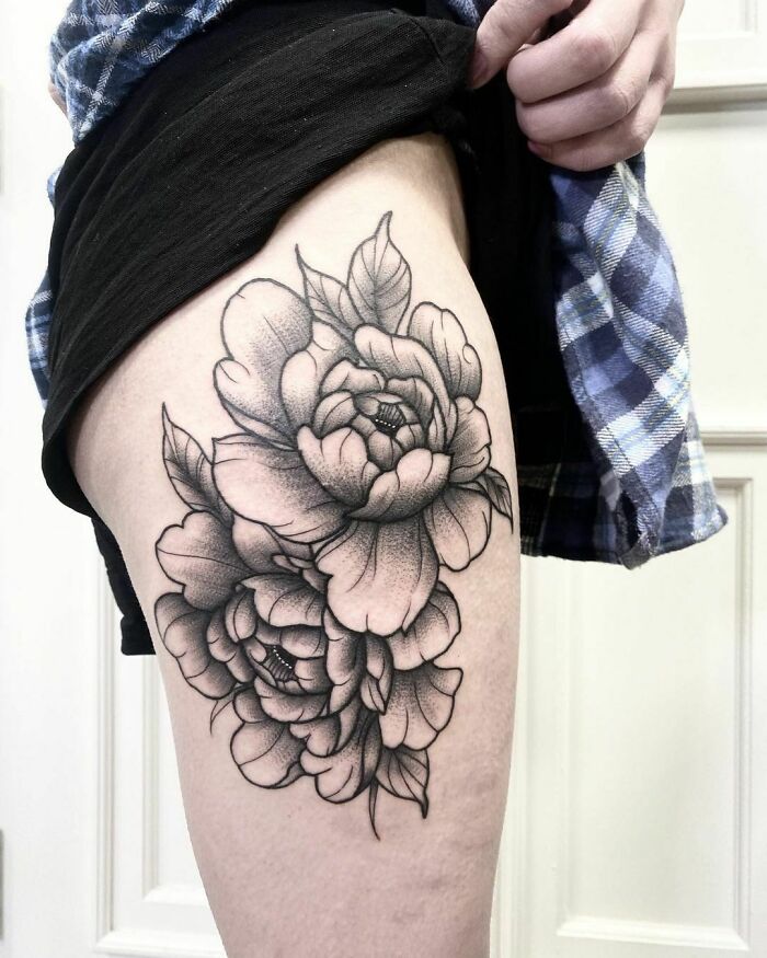 Elegant flower tattoo design in black ink on a person's thigh, showcasing beauty and artistry.