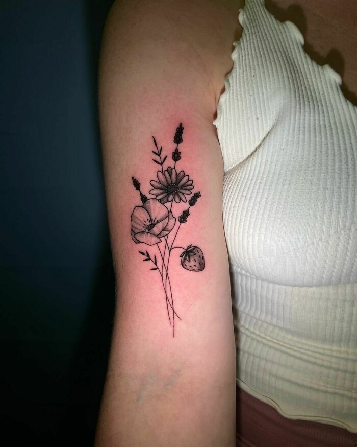 Elegant flower tattoo with a daisy and poppy on arm, showcasing beauty and style.