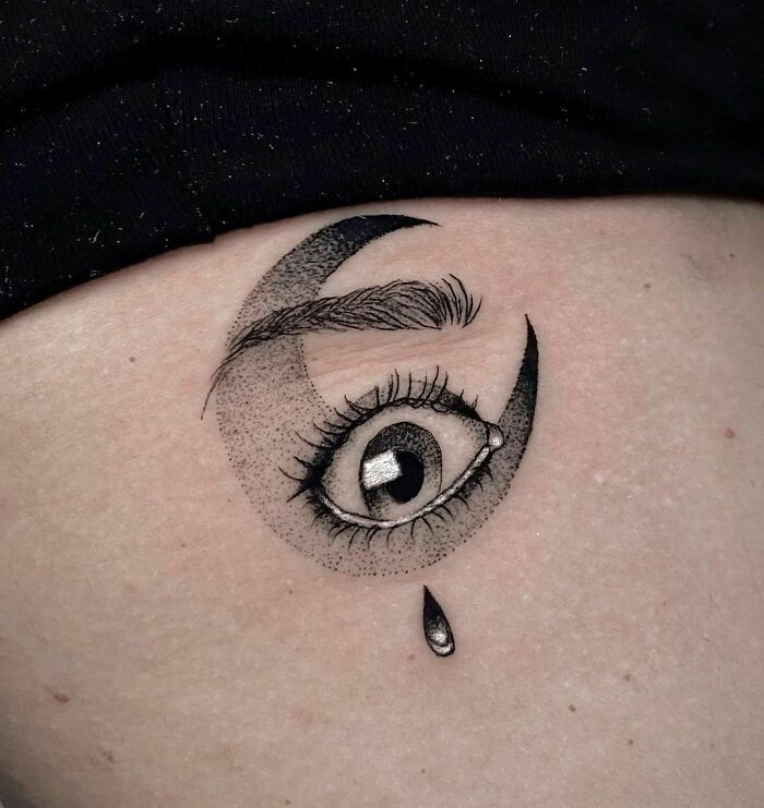 Self-love tattoo design of an eye with a crescent moon and teardrop, symbolizing introspection and emotion.