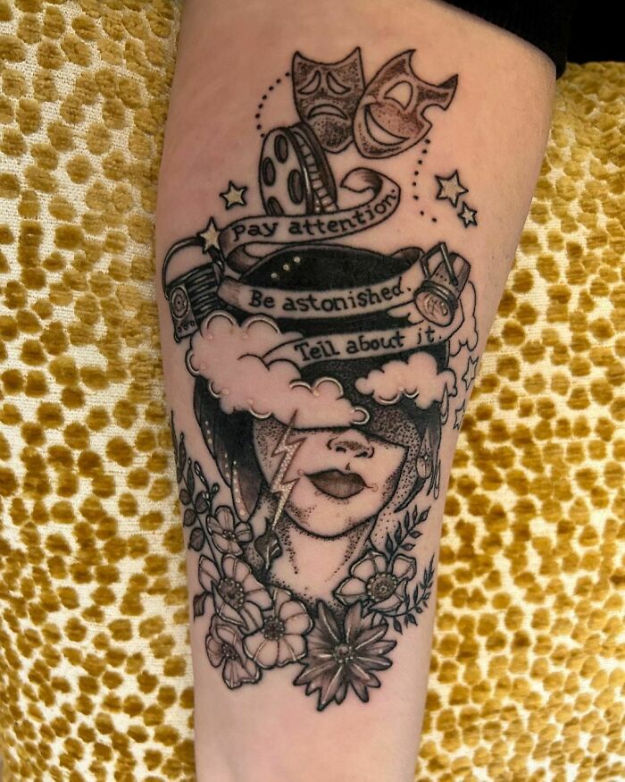 Tattoo with artistic design of a face, flowers, and inspirational quotes reflecting self-love themes.