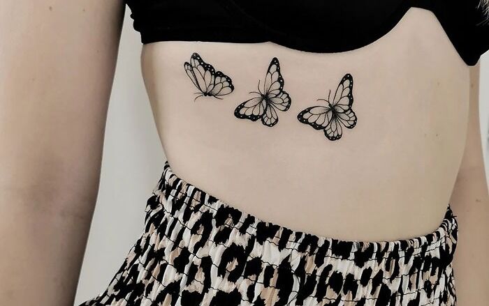 Three realistic butterfly tattoos on a person's side, emphasizing simplicity in animal tattoo designs.