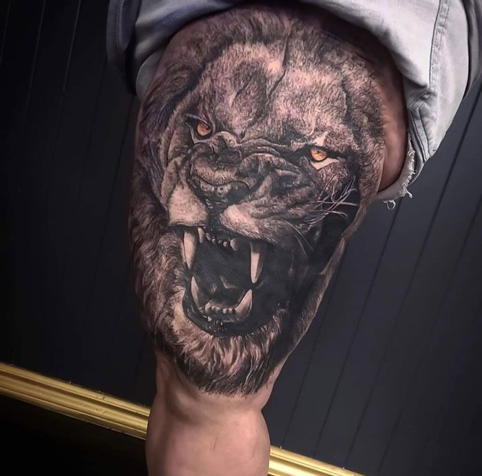 Realistic lion tattoo on thigh showcasing both simplicity and intricate detail in the design.