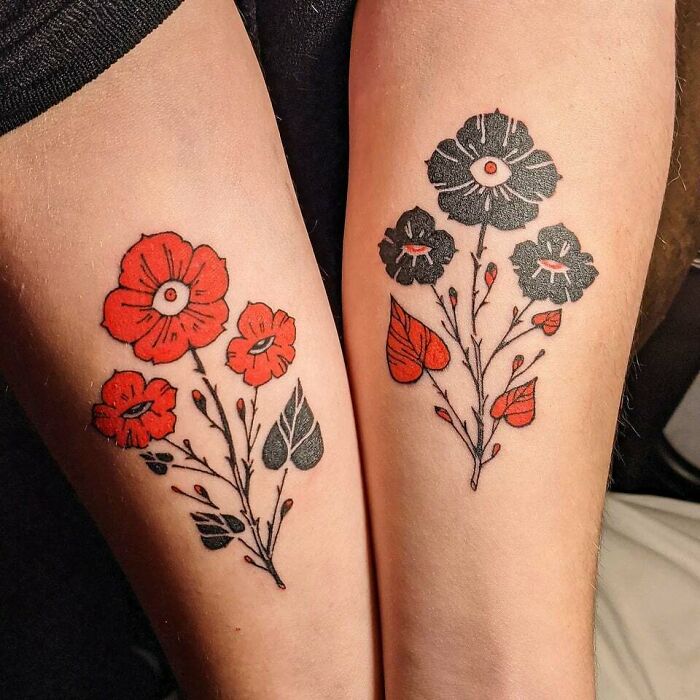Flower tattoos on arms featuring red and black floral designs, radiating elegance and beauty.