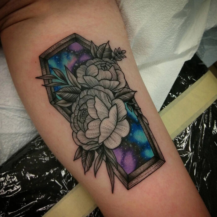 Elegant flower tattoo with intricate lines and galaxy background on arm.