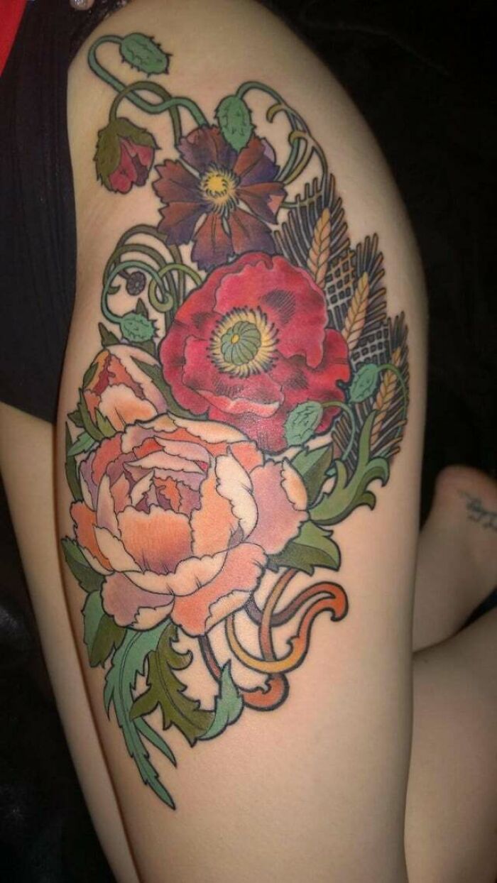 Elegant flower tattoo with vibrant colors and intricate design on arm.