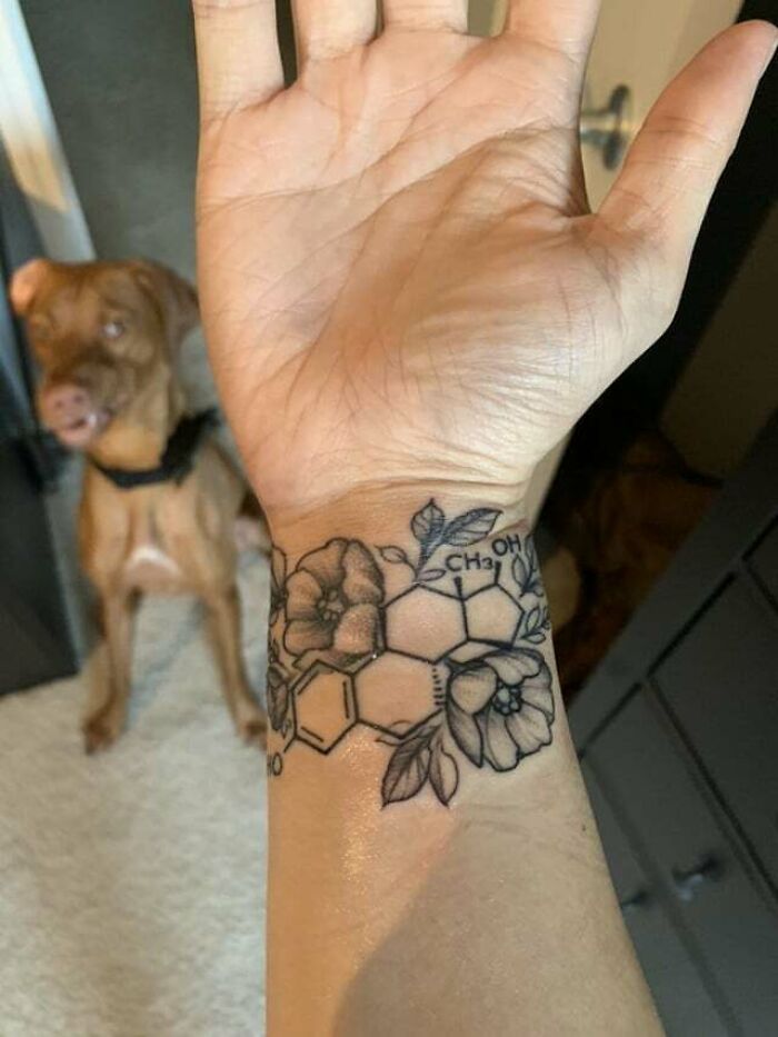 Flower tattoo on a wrist incorporating chemical structure, showcasing elegance and beauty.